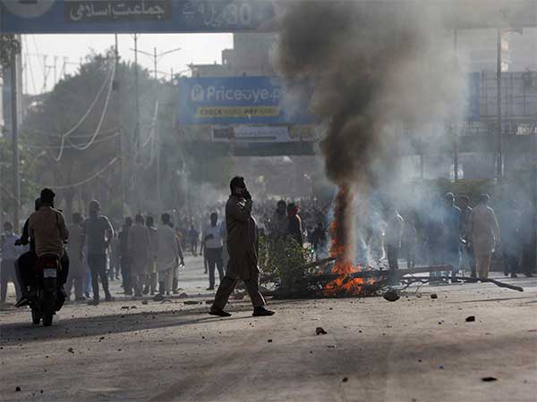A man crosses a road past a barricade that was set afire by the supporters of Pakistan's former Prime Minister Imran Khan during a protest against his arrest, in Karachi on May 9, 2023 (Image/Reuters)