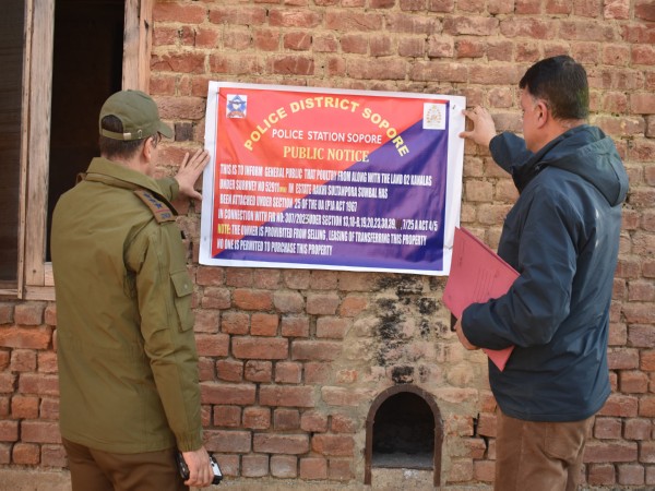 Officials attaching a public notice for general information on the property (Photo/Sopore police)