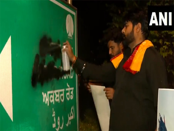 Men defacing the signboard of 'Akbar Road' in New Delhi (Photo/ANI)