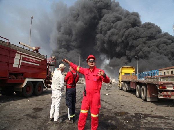 Firefighters work as smoke from the explosion is seen at the Shahid Rajaee port in Iran's Bandar Abbas (Image Credit: Reuters)