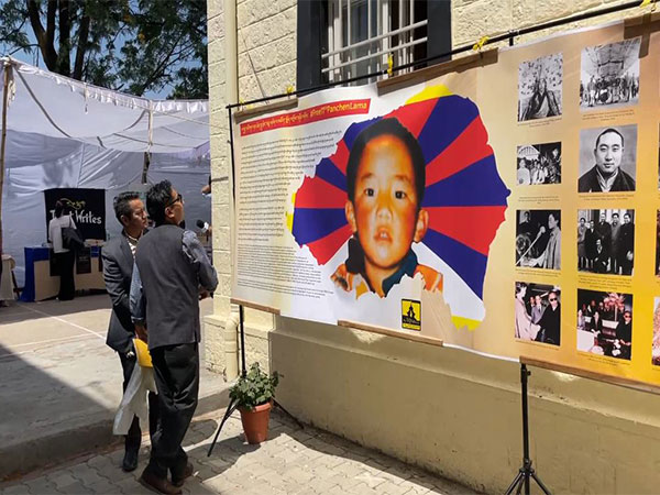 People watch poster of 11th Panchen Lama Gedhun Choekyi Nyima (File Photo/ANI)