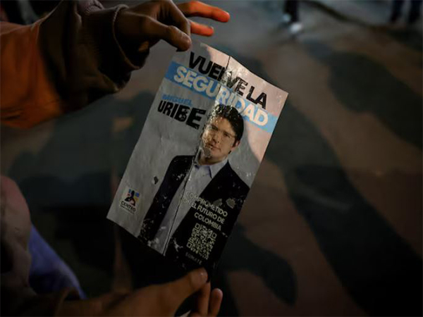 A person holds a campaign poster at the area where Colombian Senator Miguel Uribe Turbay of the opposition Democratic Center party, was shot during a campaign event, in Bogota (Image/Reuters)