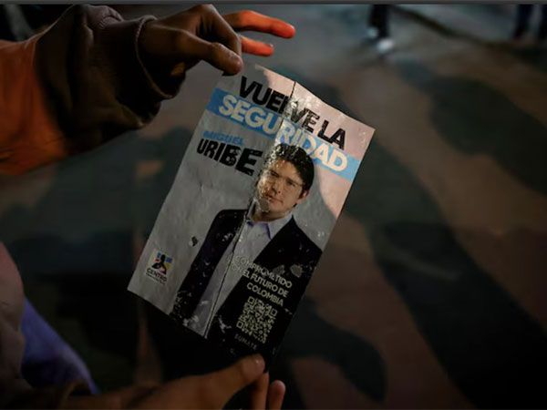 A person holds a campaign poster at the area where Colombian Senator Miguel Uribe Turbay of the opposition Democratic Center party, was shot during a campaign event, in Bogota (Image/Reuters)
