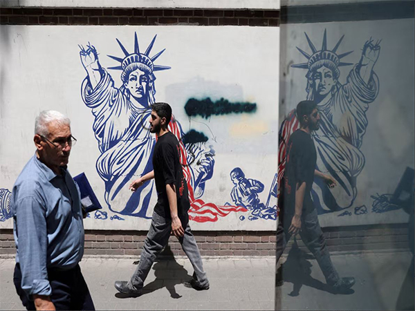 People walk past an anti-US mural on a street in Tehran (Image/Reuters)