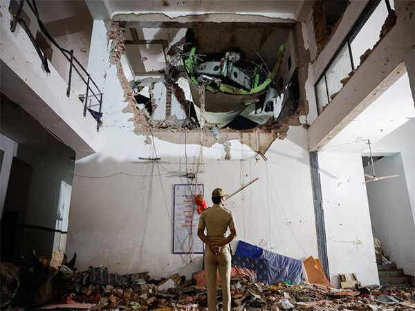 A police officer stands in front of the wreckage of an Air India aircraft, bound for London's Gatwick Airport, which crashed during take-off from an airport in Ahmedabad (Image/Reuters)