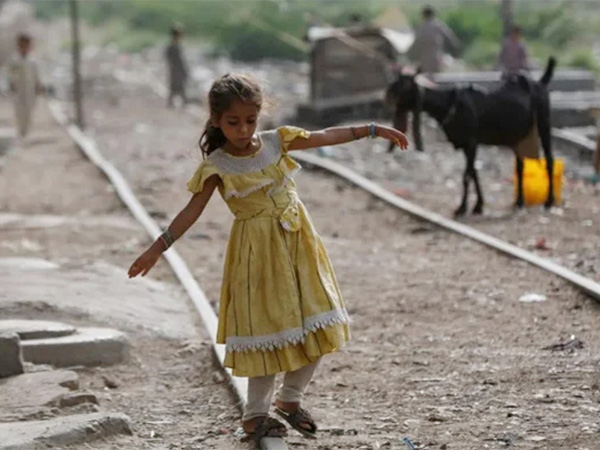 A girl balances herself while walking on an abandoned railway track in a slum area in Karachi (Image/Reuters)