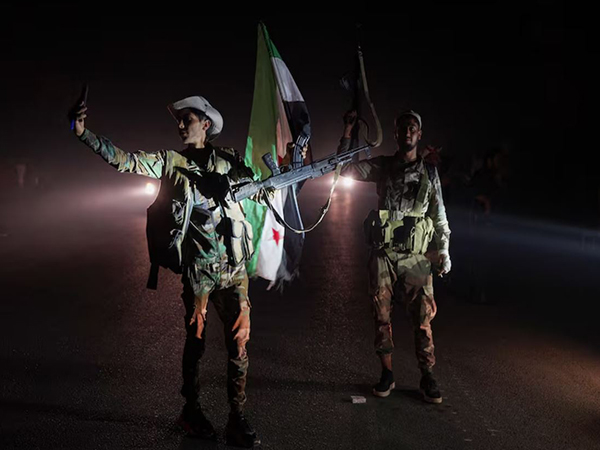 Members of Syrian security forces stand on a road in Sweida countryside, as vehicles transporting other Syrian security forces make their way out of the predominantly druze city of Sweida (Image/Reuters)