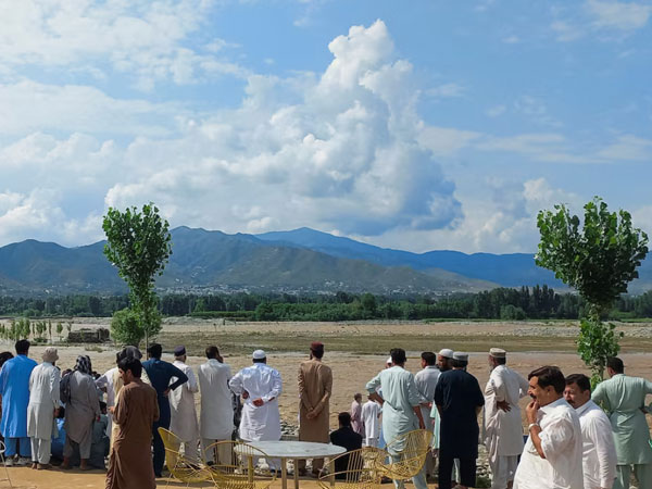 Residents gather, after tourists, who were on a picnic, were swept away by overflowing floodwaters in the Swat River on June 27 (Photo/ Reuters)