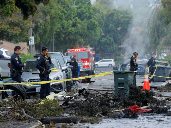 Emergency personnel work at the crash scene on a street, after a small civilian aircraft went down in a military neighborhood in San Diego (Image/Reuters)