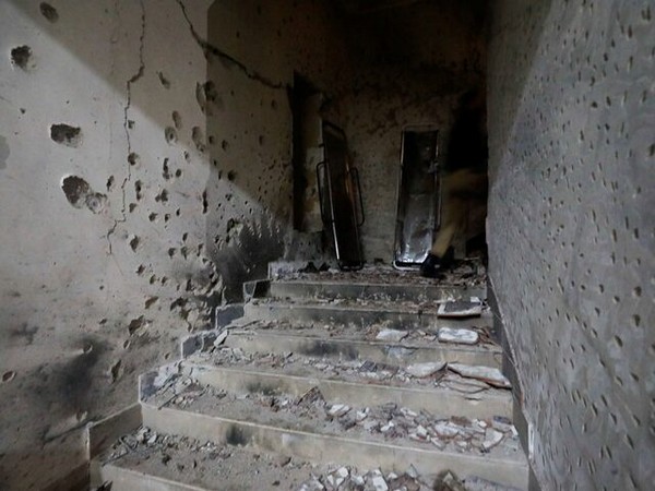 Police officers walk past stretchers amid the damages in the aftermath of an attack on a police station in Karachi (Image/Reuters)