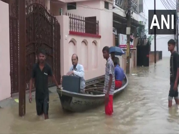 A man using a boat to commute to his work in Prayagraj's Karela Bagh area (Photo/ANI)