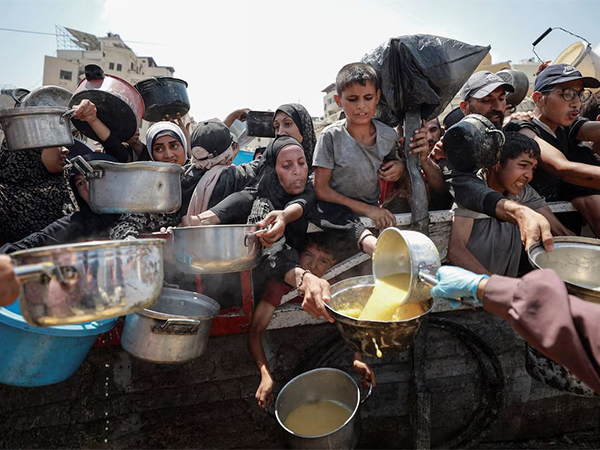 Palestinians gather to receive food from a charity kitchen in Gaza City (File Photo/Reuters)