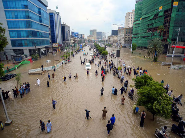 People navigate a waterlogged road following heavy monsoon rains in Karachi, Pakistan (File Photo/Reuters)