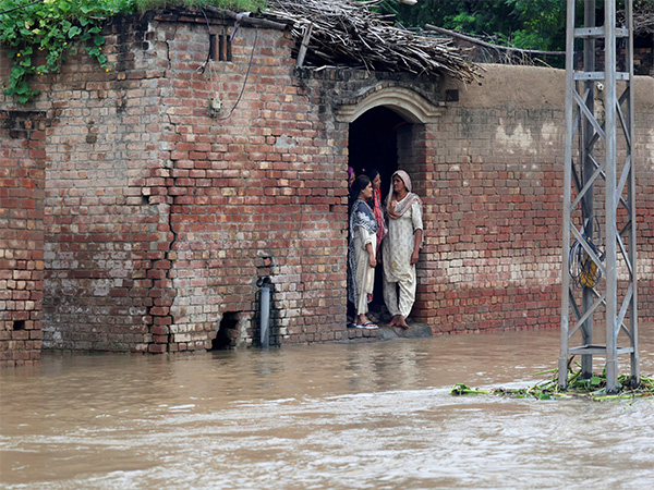 Residents stand at the entrance of a house on a flooded road after monsoon rains and rising Sutlej River levels in Hakuwala village near the Pakistan-India border in Kasur district, Punjab province (Photo/Reuters)
