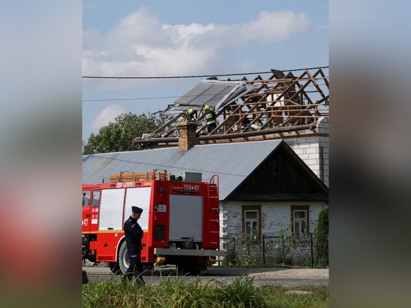 A police officer stands as firefighters work on the destroyed roof of a house in Wyryki, Lublin Voivodeship, Poland (File Photo/Reuters)