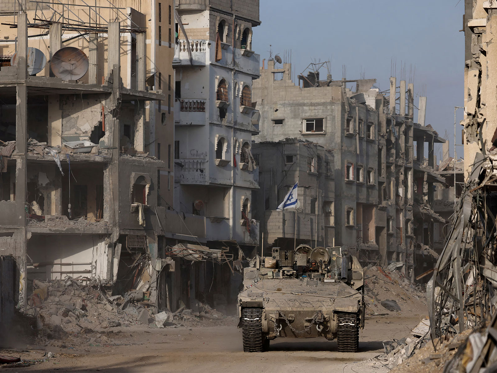 An armoured vehicle moves past damaged buildings during the ongoing Israeli ground operation against Hamas in the Gaza Strip (File Photo/Reuters)