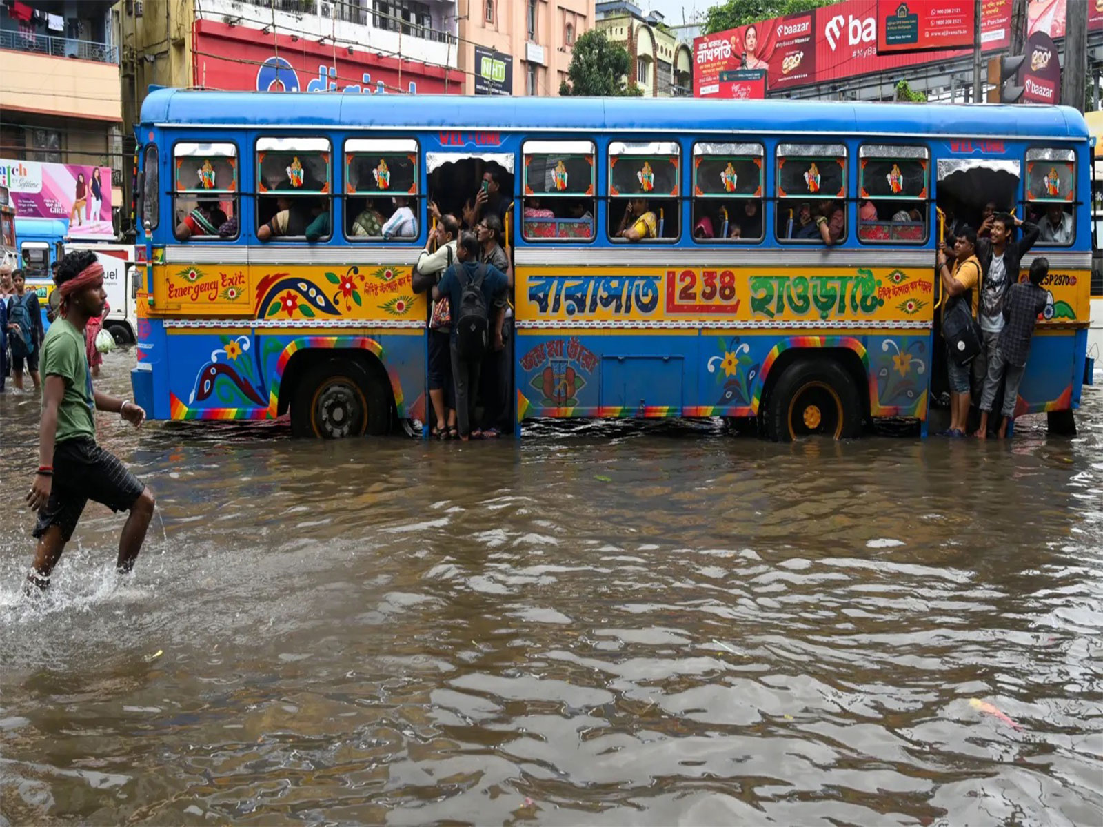 A passenger bus navigating through a waterlogged road (Pic/Shashi Tharoor/ X)