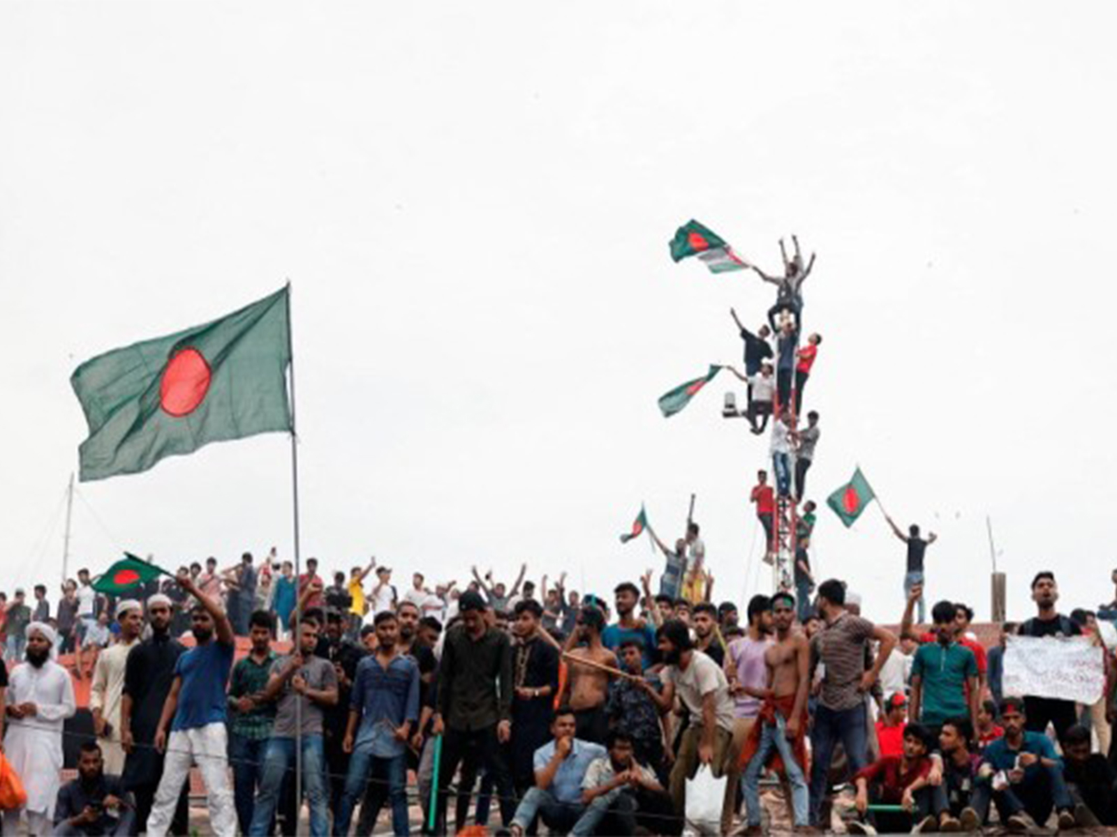 People wave Bangladeshi flags atop Ganabhaban, the Prime Minister’s residence, during celebrations following the resignation of PM Sheikh Hasina, in Dhaka (File Photo//Reuters)