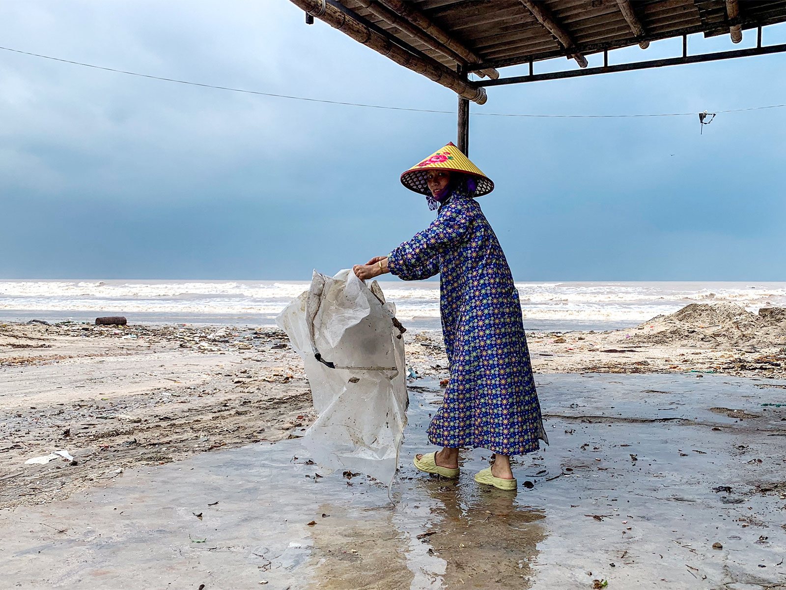 A woman wearing a raincoat collects a plastic bag near a beach as Typhoon Bualoi nears (Photo/ Reuters) A woman wearing a raincoat collects a plastic bag near a beach as Typhoon Bualoi nears (Photo/ Reuters)