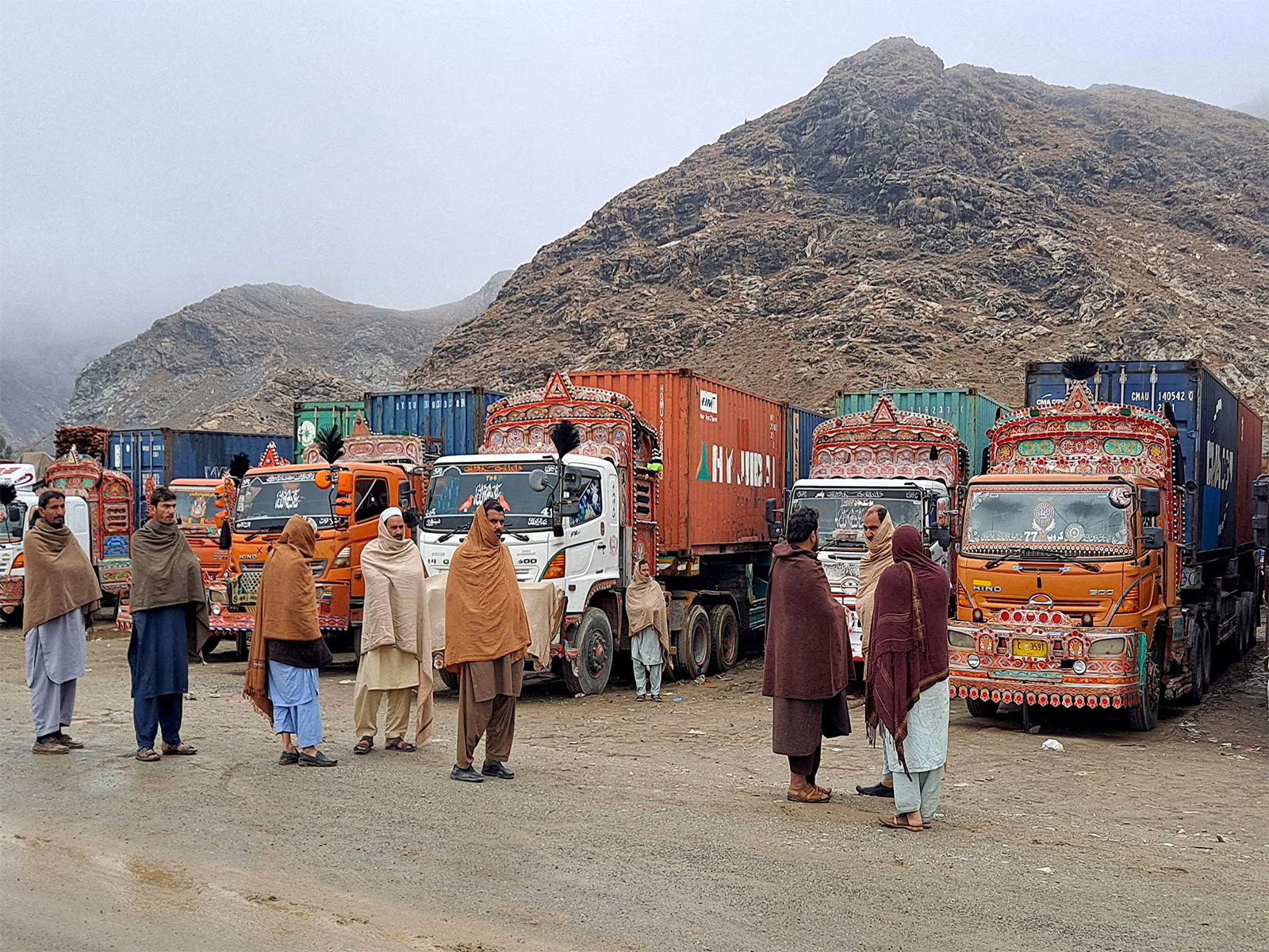 People stand beside trucks loaded with supplies at the Torkham crossing after the border between Pakistan and Afghanistan was closed. (File Photo/Reuters)