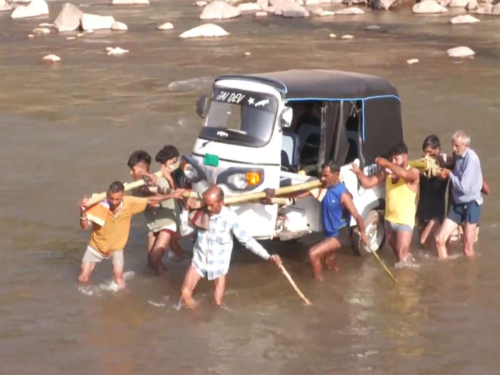 Villagers from Bant Village of Jammu and Kashmir's Udhampur district carried an Auto Rickshaw on their shoulders to cross a river, after heavy rains washed away a key bridge in recent times. (Photo/ANI)