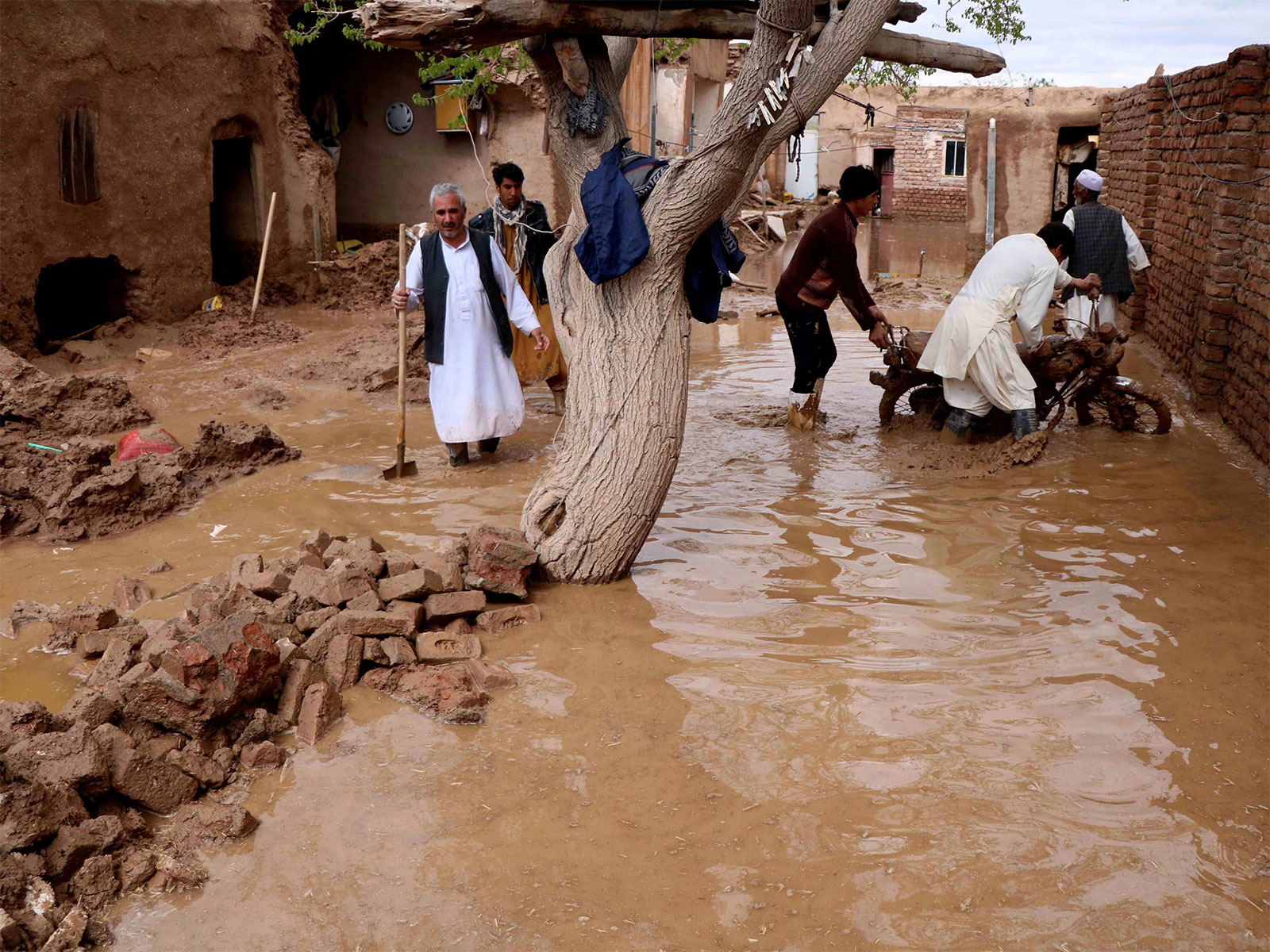 Residents clear debris and wade through floodwater after heavy rains and flash floods hit parts of Afghanistan. (File Photo/Reuters)