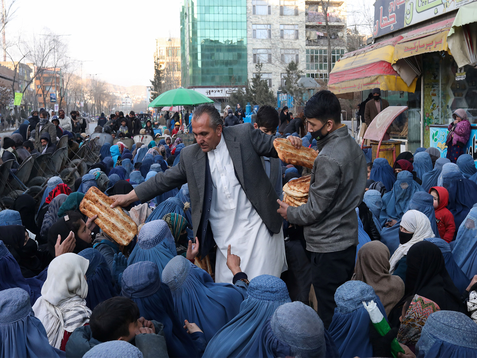 Mehr del Khan Rahmati, a bakery manager, distributes bread to the needy outside a bakery in Kabul, Afghanistan. (File Photo/Reuters)
