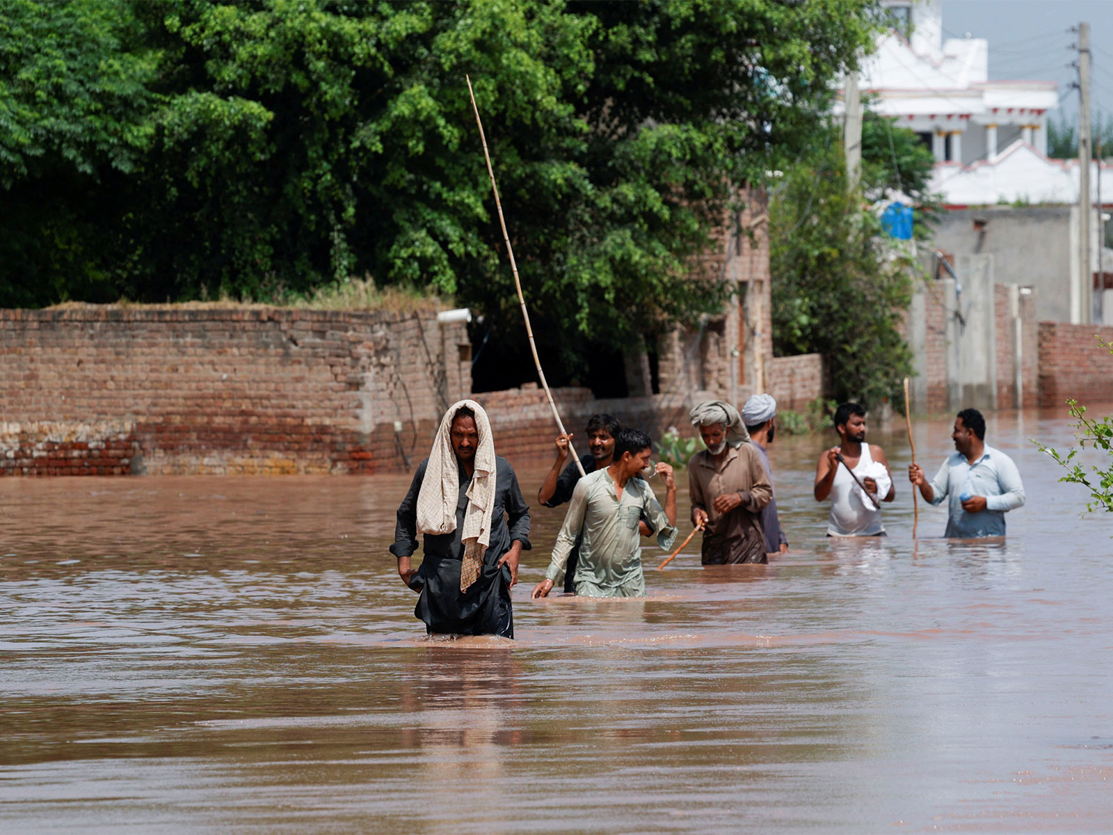 Residents wade through a flooded street after heavy monsoon rains and rising water levels near the Chenab River in Qadirabad village, Punjab province, Pakistan. (File Photo/Reuters)