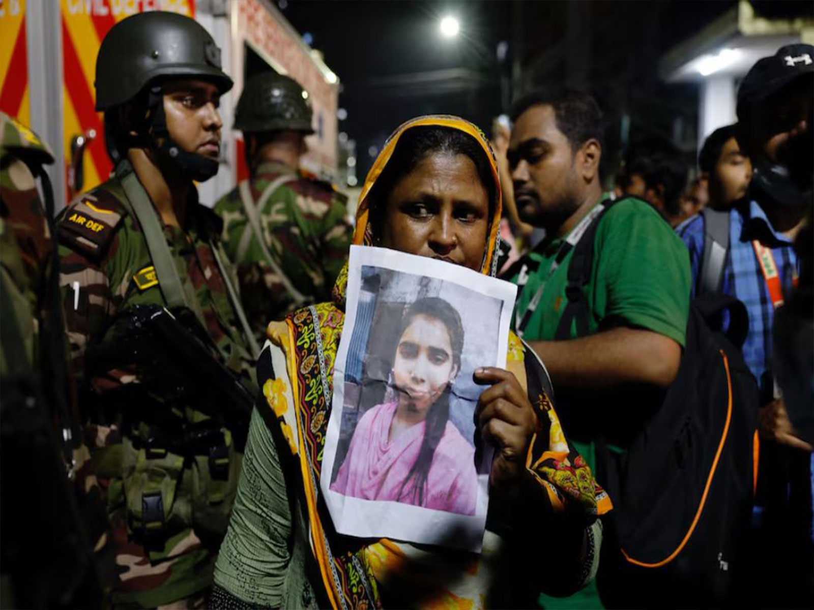 A relative mourns while holding a picture of a missing girl following a fire that broke out at a garment factory and a chemical warehouse in Dhaka (Photo/Reuters)