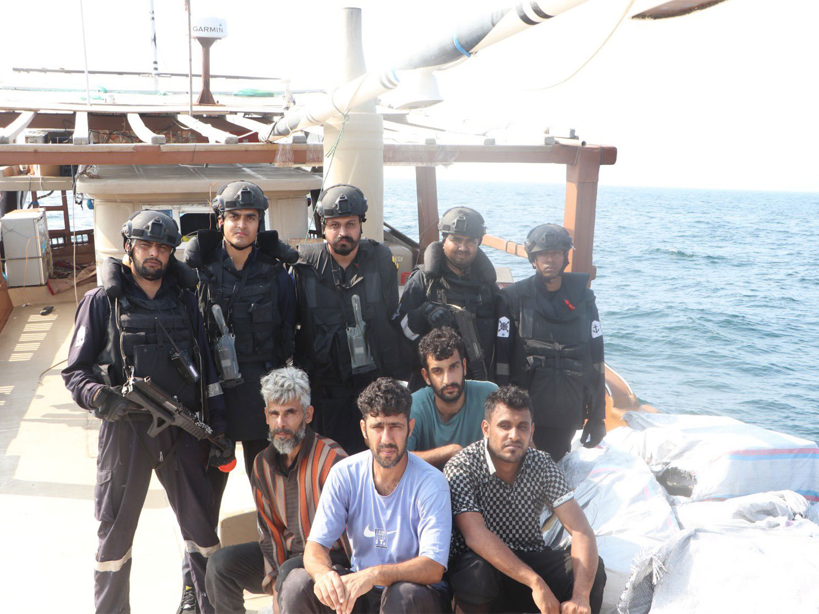 Indian Coast Guard personnel pose with detained foreign crew members and seized cartons of smuggled foreign-brand cigarettes aboard the intercepted vessel in the Arabian Sea. (Photo: X/@IndiaCoastGuard)