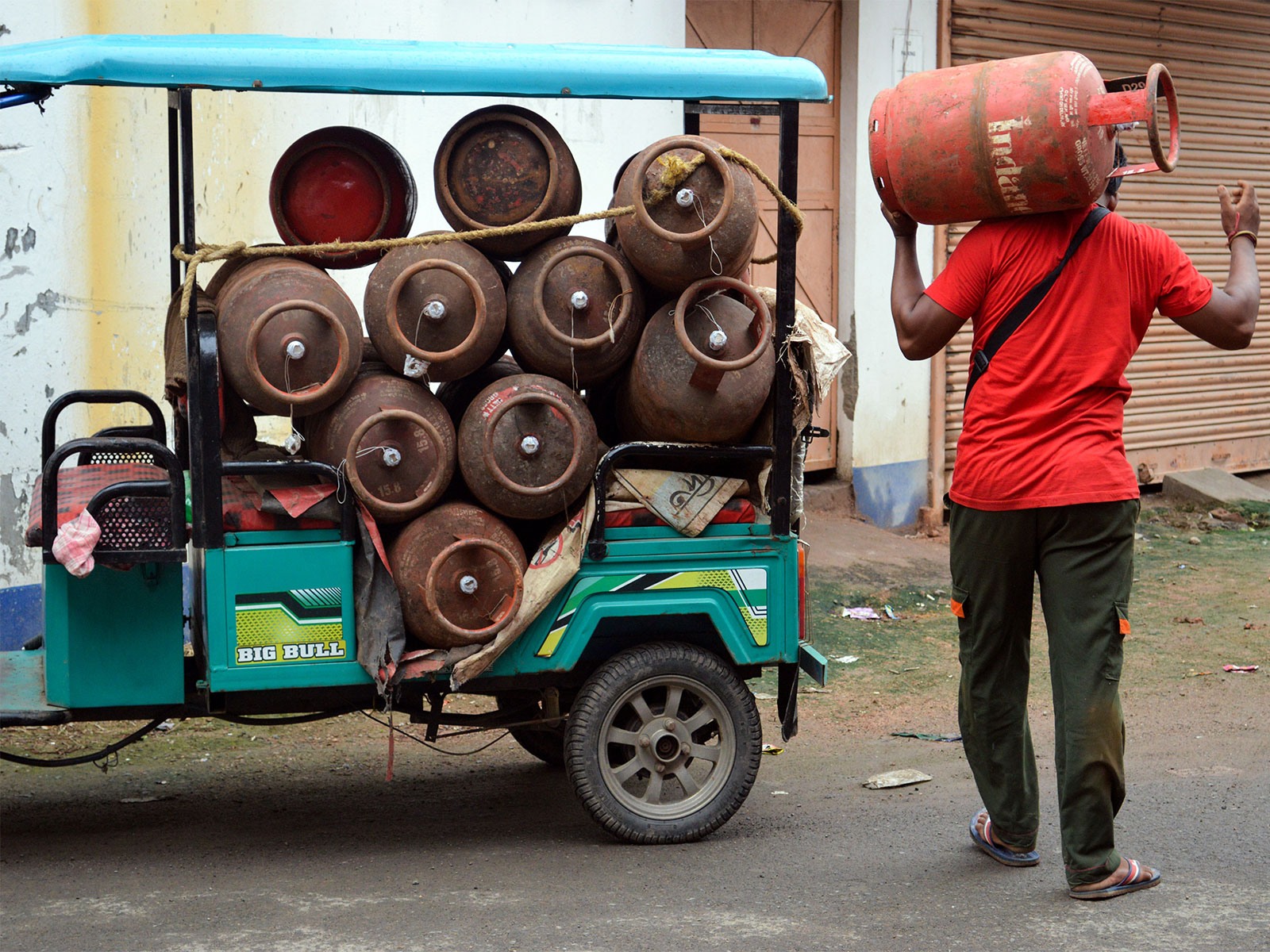 A worker carries LPG gas cylinders for delivery. (Photo/ANI)