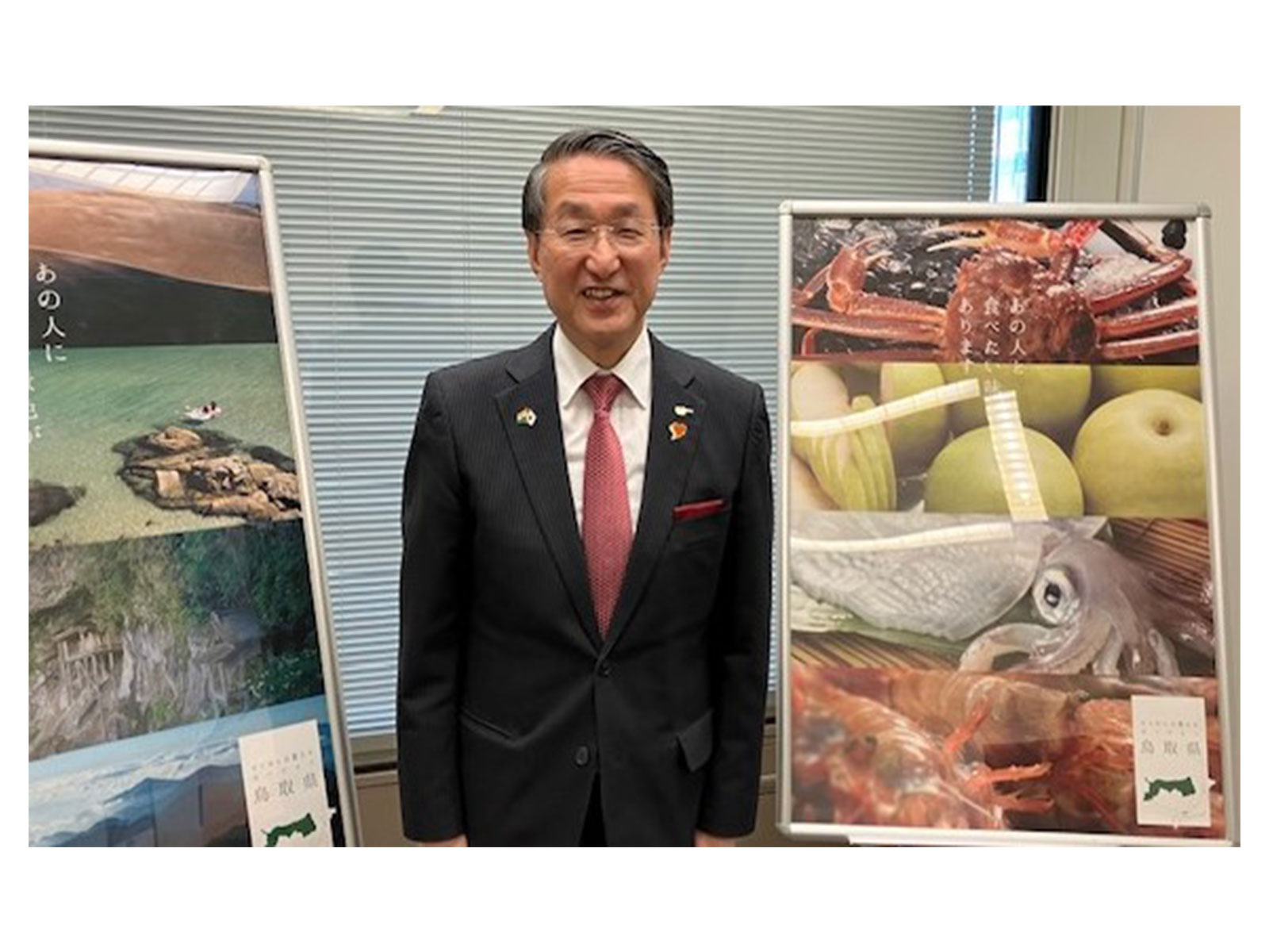Tottori Prefecture Governor Shinji Hirai poses beside display boards showcasing local seafood and scenic landscapes (Photo/ANI) Tottori Prefecture Governor Shinji Hirai poses beside display boards showcasing local seafood and scenic landscapes (Photo/ANI)