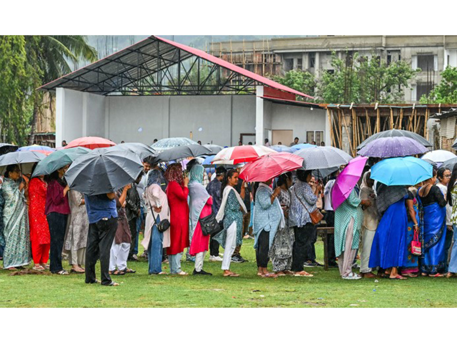 Voters queue up to cast their votes amid rain at a polling station in Assam (Photo/ANI)