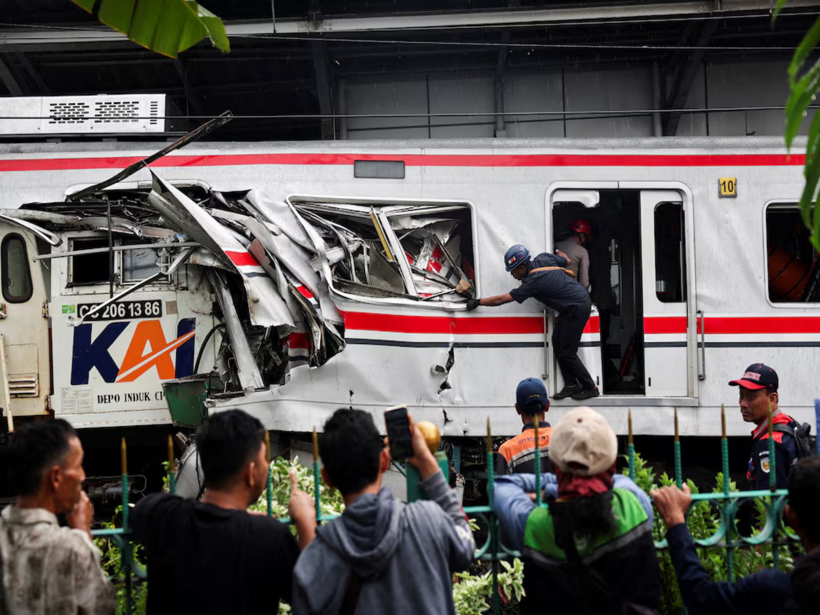 People look on as a technician works at the site of a deadly collision between a commuter train and a long-distance train in Bekasi, on the outskirts of Jakarta, Indonesia. (Photo/Reuters)