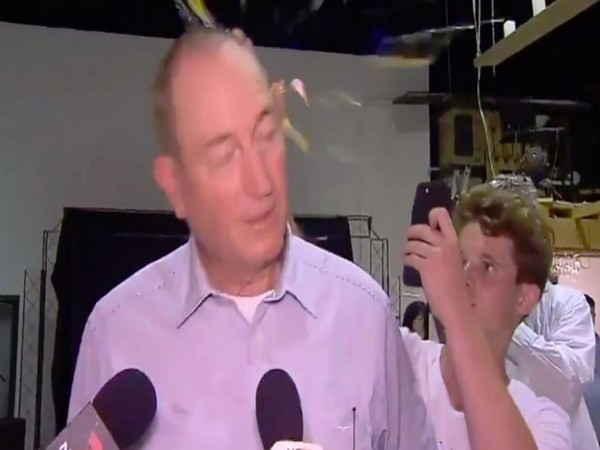 A teenager smashes an egg at Queensland Senator Fraser Anning's head during a news conference in Melbourne on Saturday. (CREDITS: TV GRAB)