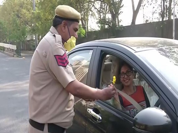 Delhi police personnel offering flowers to commuters on Sunday. Photo/ANI