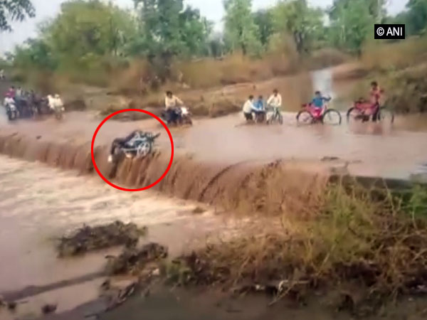 Man riding bike swept away by flood waters in Khargone, Madhya Pradesh on Wednesday. [Photo/ANI]