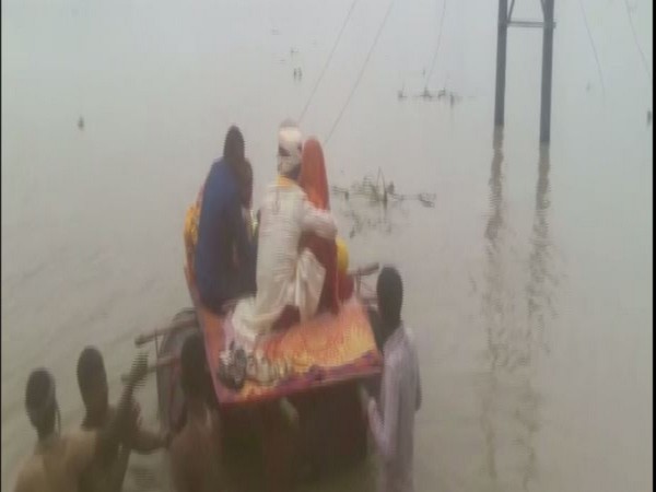 A bride and a groom cross a flooded street in Forbesganj on a makeshift pontoon boat made out of plastic drums.
