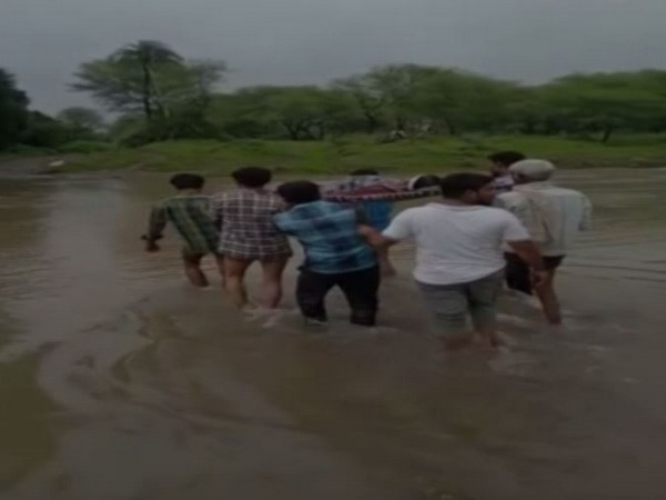 Locals carried a pregnant woman on a cot amid heavy rainfall in Sehore Village, Madhya Pradesh. (Photo/ANI)