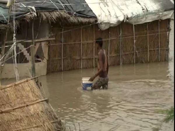 A man trying to cross the flooded road in Yamuna Khadar on Tuesday (Photo/ANI)