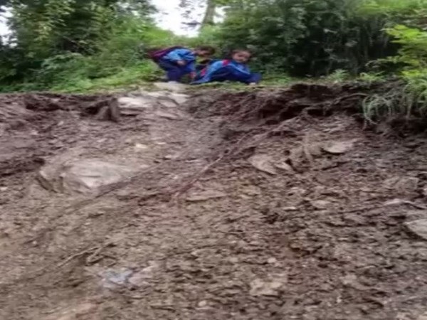 School children face major problem while crossing damaged roads in Chamoli district followed by incessant rains. (Photo/ANI)