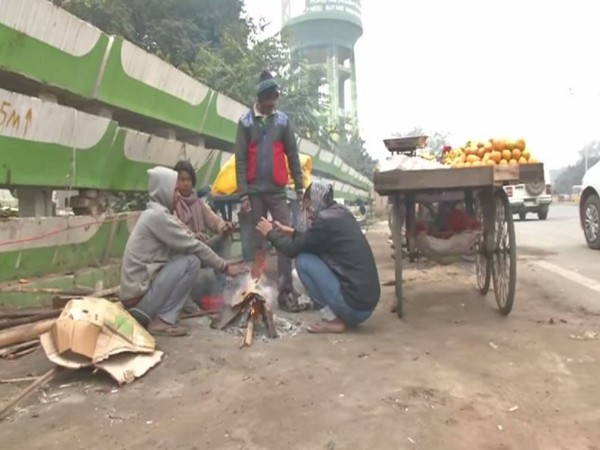 Street vendors sit around a bonfire to keep themselves warm in Patna on Monday (Photo/ANI)