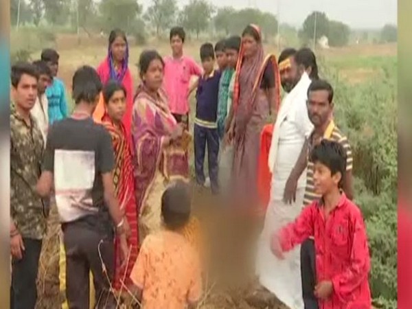    Taj Sultanpur villagers of Kalaburagi district overseeing disabled children (blurred face) buried neck-deep in the soil during the solar eclipse here on Thursday. 