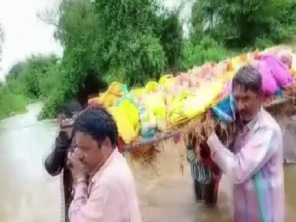 Villagers were forced to take dead body of an elderly woman through flooded drains in Mandsaur. Photo/ANI