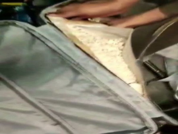 Heroin being recovered from the trolley bags carried by the accused.