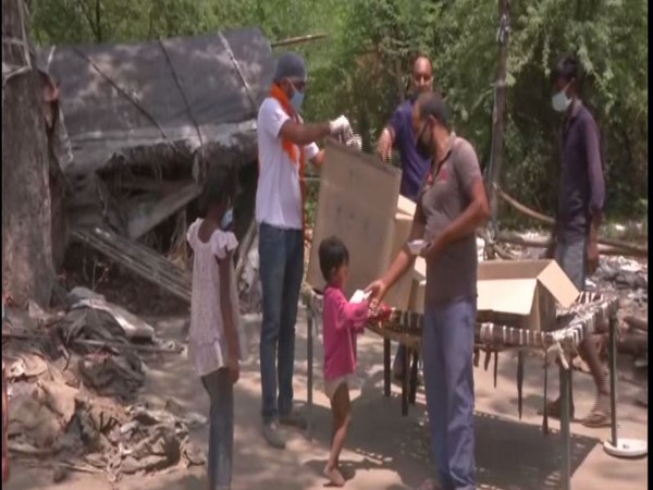 BJP's Good Governance Cell providing food to a child in Chilla Khadar village on Thursday.  Photo/ANI 