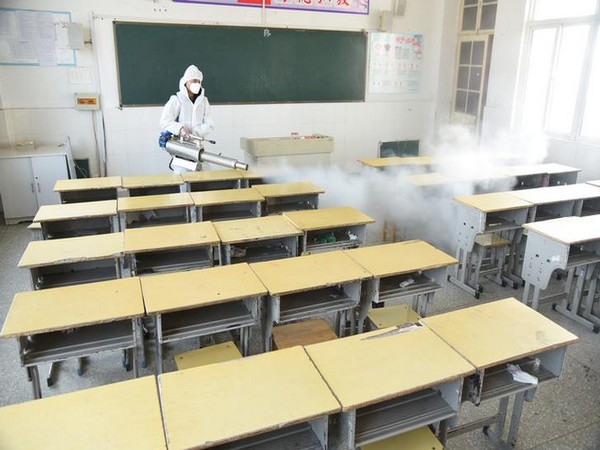 A worker in a protective suit sprays disinfectant inside a classroom of a primary school in Jiangsu province, China
