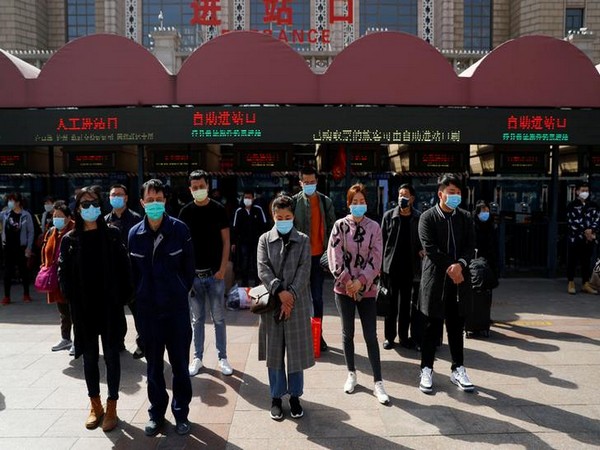 People wearing face masks stand to pay tribute as China holds national mourning for those who died of the coronavirus disease in Beijing