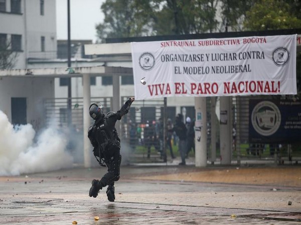 A riot police officer throws a tear gas canister during a protest in Bogota.