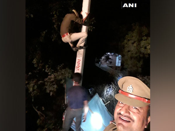 Sub-inspector clicking photo with constable who climb up the electricity pole to remove posters in Unnao, Uttar Pradesh.